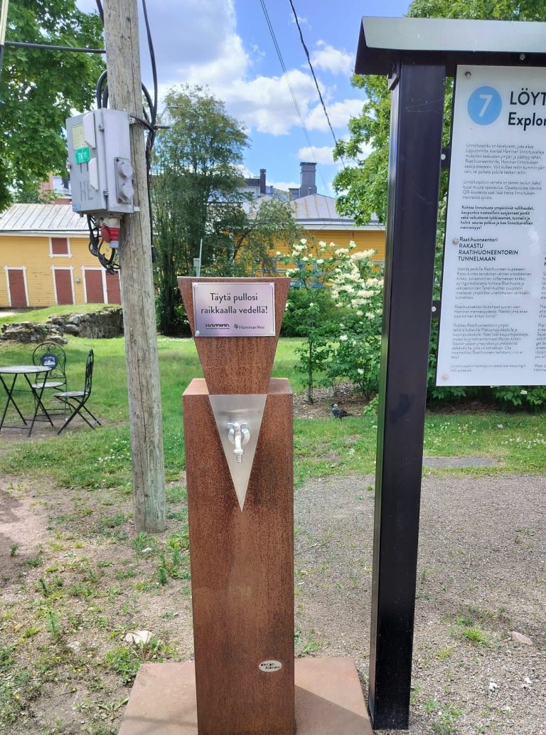 Veistoksellinen vesiposti hanalla.